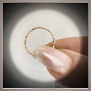 May include: A thin gold band ring with small diamonds set in the band.