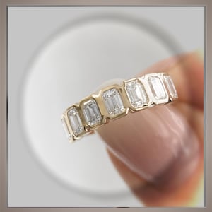 May include: A gold band ring with a row of emerald-cut diamonds.
