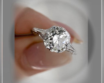 May include: A silver engagement ring with a large, round, clear diamond set in a delicate, filigree design.