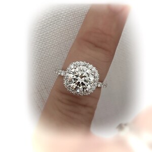 May include: A silver ring with a large, round, clear diamond surrounded by a double halo of smaller diamonds.