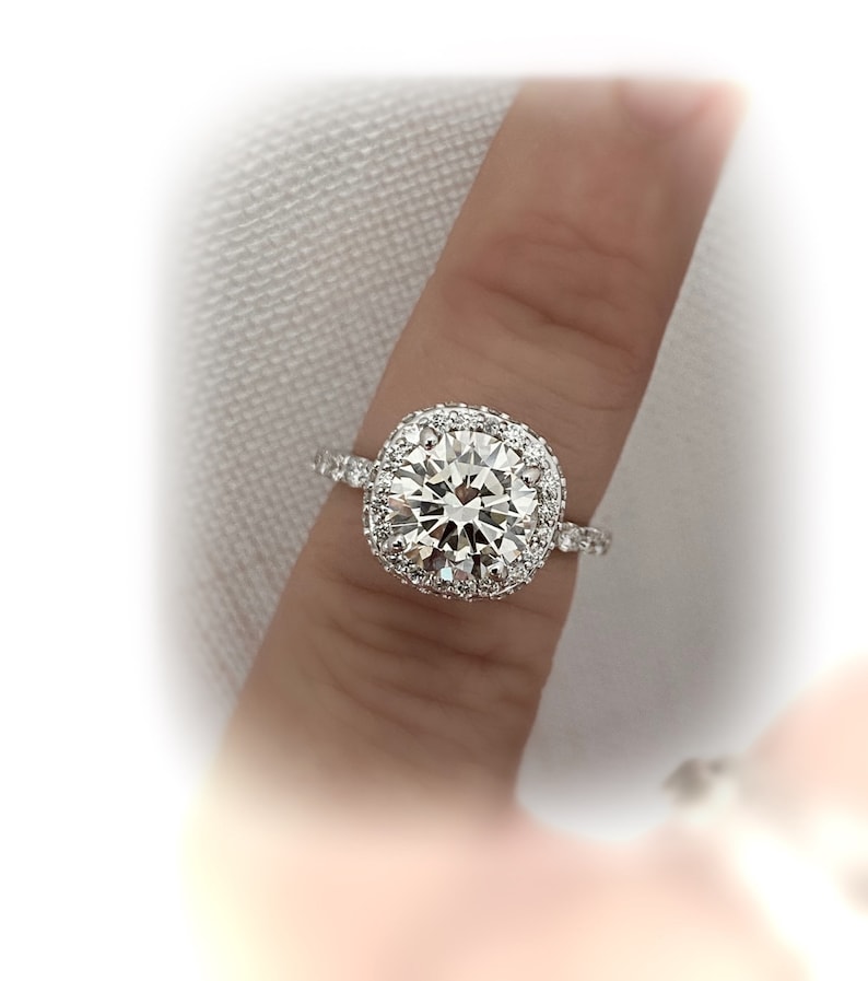 May include: A silver ring with a large, round, clear diamond surrounded by a double halo of smaller diamonds.