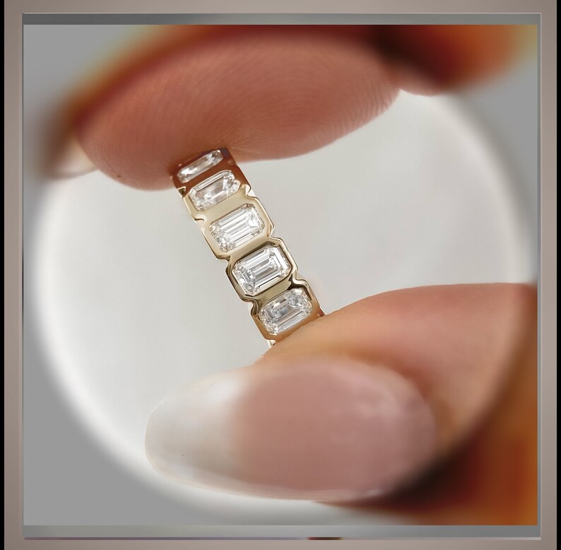 May include: A gold band ring with a row of emerald-cut diamonds.
