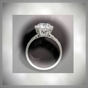 May include: A silver ring with a large, clear, round diamond set in a delicate, intricate design.