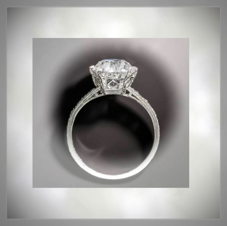 May include: A silver ring with a large, clear, round diamond set in a delicate, intricate design.
