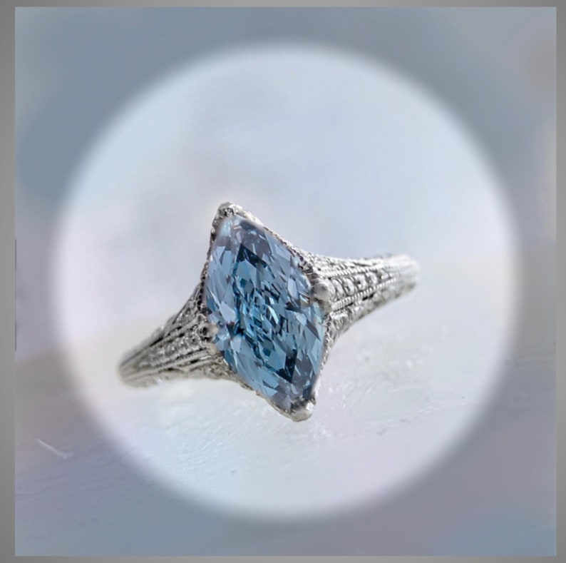 Pu&ograve; includere: Un anello d'argento con una pietra preziosa di forma marquise blu chiaro incastonata in un design a filigrana.