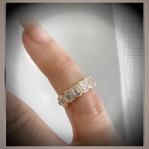 May include: A gold band ring with a row of emerald-cut diamonds.