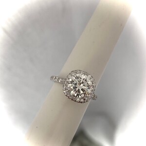 May include: A silver ring with a large, square-cut diamond surrounded by a halo of smaller diamonds.