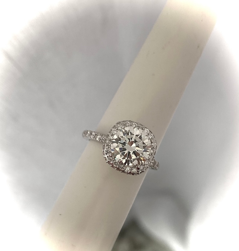 May include: A silver ring with a large, square-cut diamond surrounded by a halo of smaller diamonds.