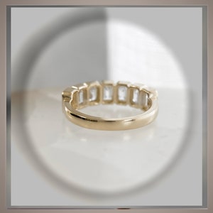 May include: A gold band with a row of clear, rectangular-shaped gemstones.