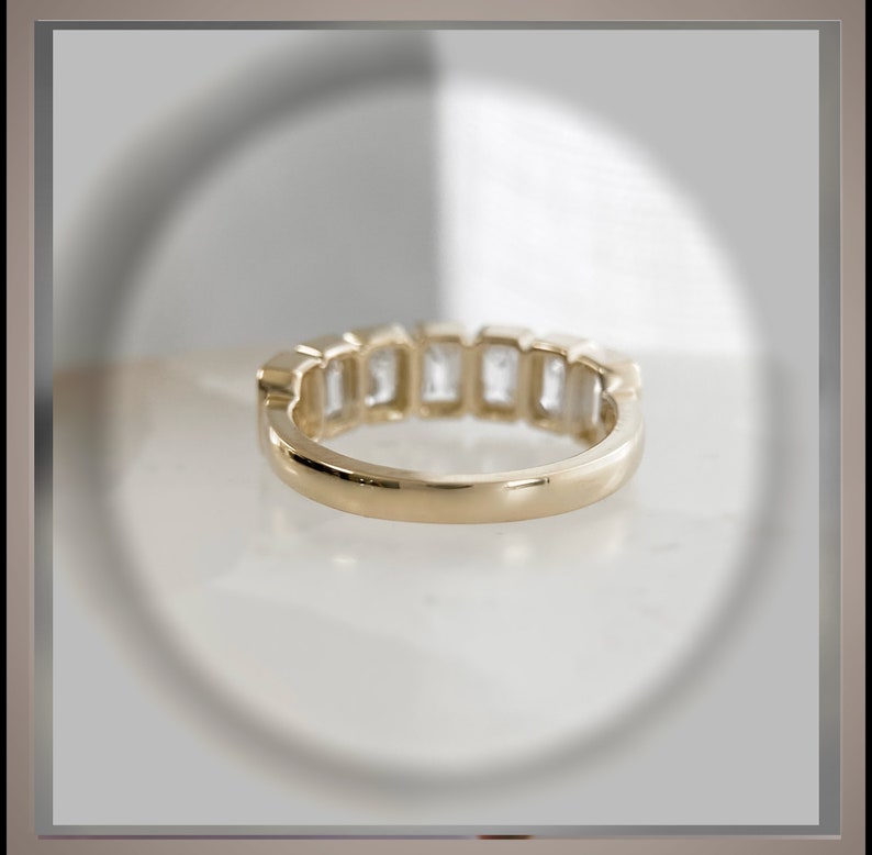 May include: A gold band with a row of clear, rectangular-shaped gemstones.