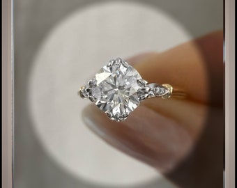 May include: A silver engagement ring with a large, round, clear diamond center stone and smaller diamonds on the band. The ring is set in a yellow gold band.