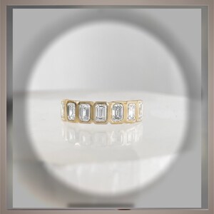 May include: A gold band ring with a row of emerald-cut diamonds.