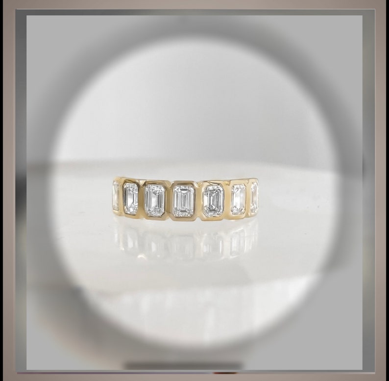 May include: A gold band ring with a row of emerald-cut diamonds.