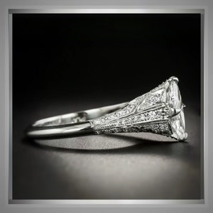 Pu&ograve; includere: Un anello di fidanzamento in platino con un grande diamante ovale incastonato a griffe. La fascia &egrave; decorata con diamanti pi&ugrave; piccoli in un design delicato e intricato.