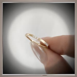 May include: A thin gold band with a row of small diamonds set into the metal.