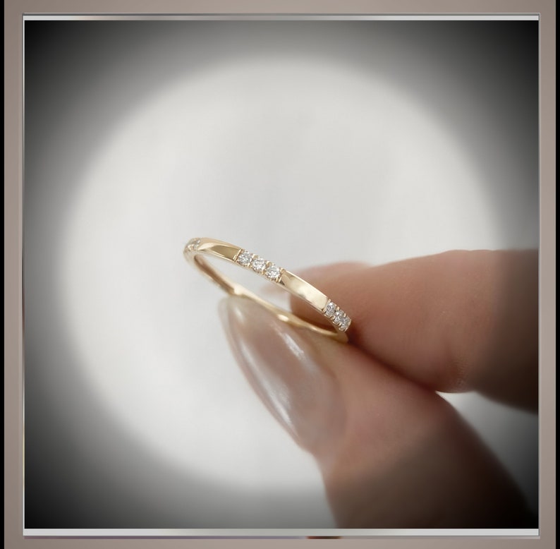 May include: A thin gold band with a row of small diamonds set into the metal.