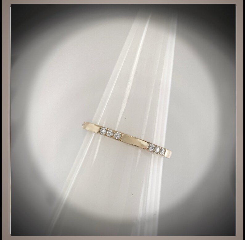 May include: A thin gold band ring with small diamonds set in a row.