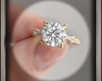 May include: A gold engagement ring with a large, round, clear diamond set in a delicate, ornate setting. The ring is on a finger.