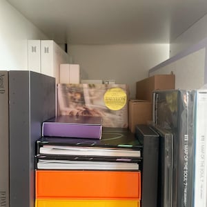 May include: A collection of music albums and box sets arranged on a shelf. Visible titles include BTS Map of the Soul 7 The Journey, Taeyeon Purpose, and Agust D D-Day. The items feature various colours including bright orange, yellow, and purple.