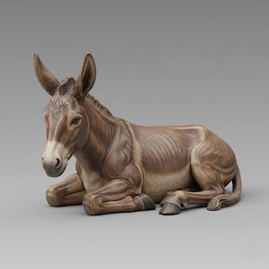 May include: A detailed figurine of a donkey in a resting pose. The donkey is primarily brown with lighter tan and white accents on its face and belly. The ears are upright, and the eyes are open. The figurine is likely made of ceramic or a similar material.