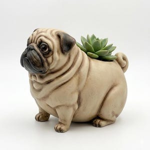 Puede incluir: Una maceta beige con forma de pug con una planta suculenta verde. El pug tiene un diseño detallado y realista con detalles en marrón oscuro en la cara y las orejas. La maceta está hecha de cerámica o un material similar.