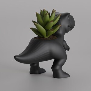 May include: A black Tyrannosaurus Rex planter with a green succulent plant. The dinosaur-shaped planter has a textured surface and is standing on two legs. The plant is in the dinosaur's back.