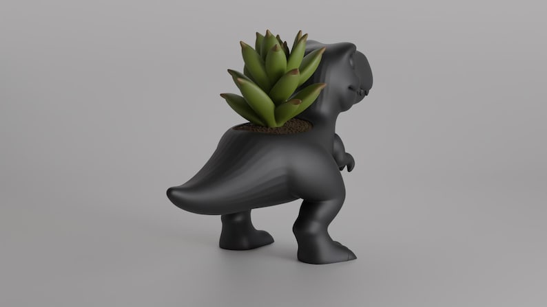 May include: A black Tyrannosaurus Rex planter with a green succulent plant. The dinosaur-shaped planter has a textured surface and is standing on two legs. The plant is in the dinosaur's back.