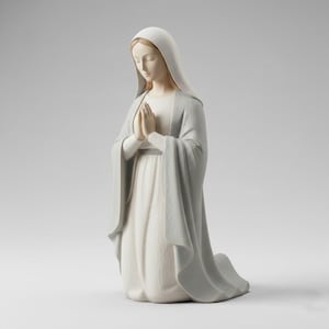 May include: A kneeling figurine of a woman in a long white dress and a light blue cloak. Her hands are clasped in prayer, and her head is bowed. The statue has a serene expression and is set against a plain background.