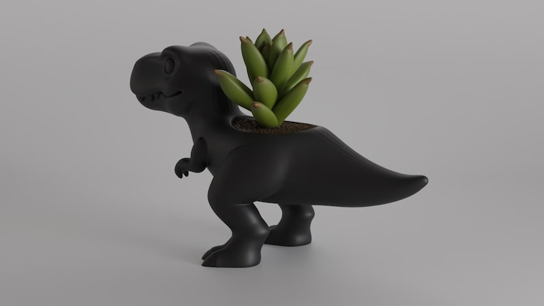 May include: A black Tyrannosaurus Rex planter with a succulent plant. The dinosaur-shaped planter is made of a matte black material. The succulent has green leaves and is planted in soil inside the dinosaur's back.