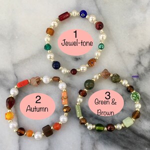 May include: Three beaded bracelets with white pearls and various colored glass beads. The bracelets are labeled 1 Jewel-tone, 2 Autumn, and 3 Green & Brown.