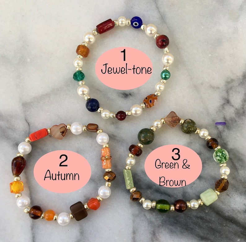 May include: Three beaded bracelets with white pearls and various colored glass beads. The bracelets are labeled 1 Jewel-tone, 2 Autumn, and 3 Green & Brown.