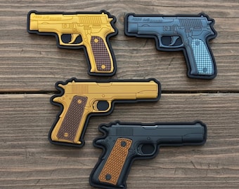 May include: Four toy gun patches in gold, blue, and black, with brown and blue grips. The patches are arranged on a wooden surface. Two patches are gold, one is blue, and one is black.