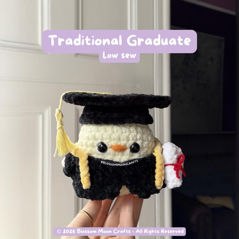 May include: A crocheted graduation-themed plushie in black, yellow, and white. The plushie wears a graduation cap and gown, and holds a diploma tied with a red ribbon. The text "Traditional Graduate" and "Low sew" are visible.