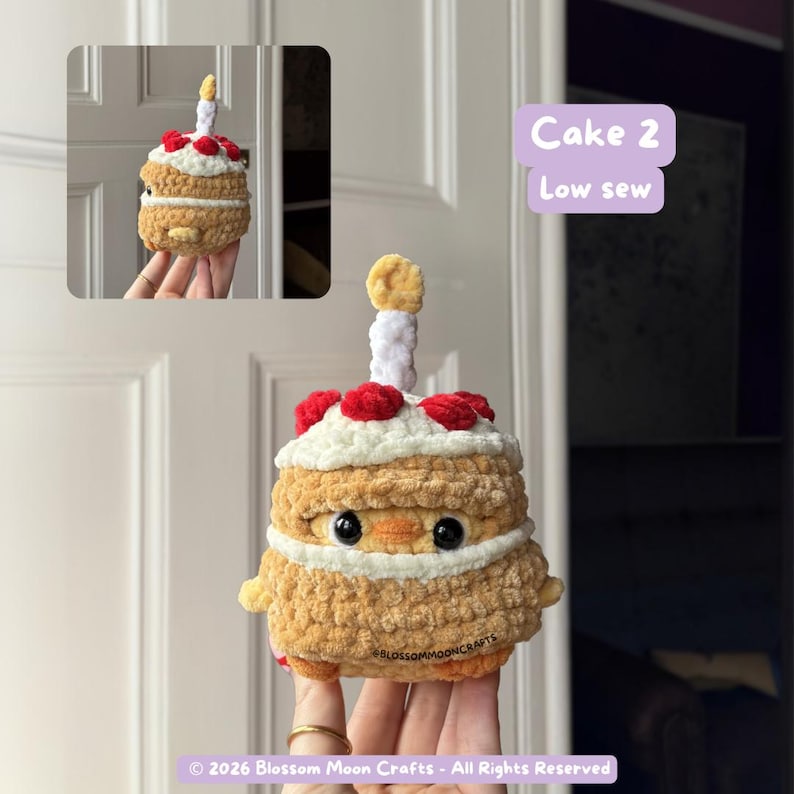 May include: A crocheted cake with a candle, red berries, and white frosting. The cake has a yellow and brown color scheme, with the text "Cake 2 Low sew" in a purple box. The cake is held in a person's hand.