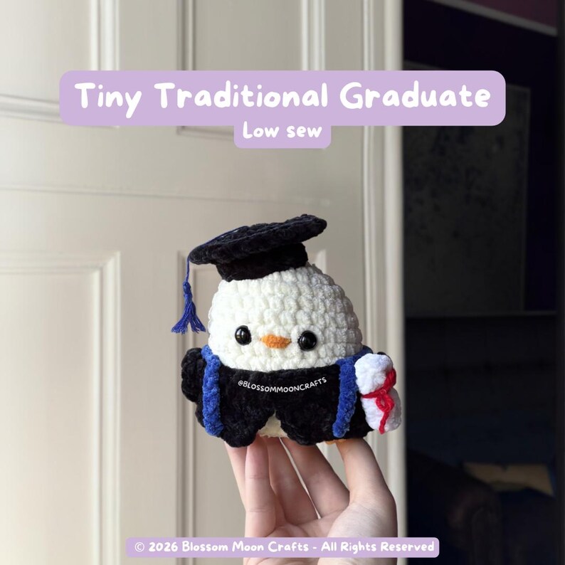 May include: A handmade crochet penguin wearing a graduation cap and gown. The penguin is white with black accents, a black cap, and a blue tassel. It holds a tiny diploma. Text on the image reads "Tiny Traditional Graduate" and "Low sew".