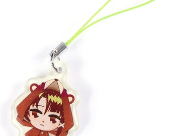 Puede incluir: Un colgante acrílico transparente con un personaje de dibujos animados con un disfraz de oso rojo. El colgante tiene un cordón verde lima sujeto con un cierre de metal plateado. El personaje tiene el pelo castaño y ojos rojos.