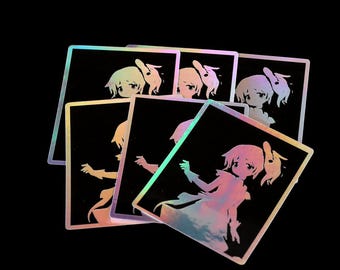 Puede incluir: Una colección de pegatinas holográficas con un personaje de estilo anime con pelo corto y un vestido fluido. Las pegatinas tienen un fondo negro y un brillo arcoíris, creando un efecto vibrante y llamativo.