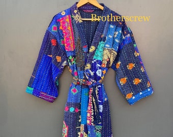 Puede incluir: Una bata kimono de patchwork azul y multicolor con un patrón floral y bordados dorados. La bata tiene un cinturón de atar y mangas largas.