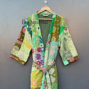 Pode incluir: Uma bata acolchoada de patchwork verde com um padrão floral. A bata tem um cinto para amarrar e é feita de um tecido macio e confortável.