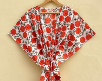 May include: A white and red floral print kaftan with a V-neckline and short sleeves. The kaftan has a tie at the waist and a long, flowing skirt.