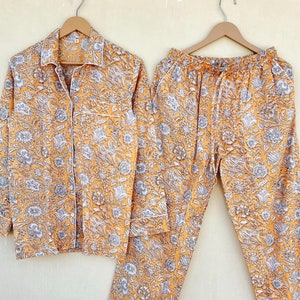 May include: A yellow and white floral print pyjama set with a long-sleeved shirt and matching trousers.