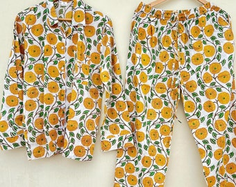 May include: A white pajama set with a yellow floral print. The top has long sleeves and a button-up closure. The pants have an elastic waistband.