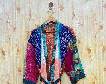 May include: A colorful patchwork kimono robe with a teal sash. The robe has a pink and white polka dot pattern on the bottom half.