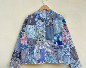 May include: A blue quilted jacket with a patchwork design featuring various floral and geometric patterns. The jacket has a mandarin collar, a button closure, and two patch pockets.