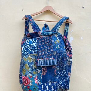 May include: A blue patchwork backpack with floral and geometric patterns. The backpack has adjustable straps and a flap closure.