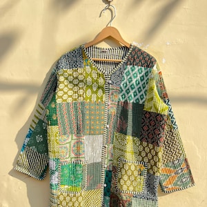 Peut inclure: Une veste matelassée patchwork verte et marron avec une fermeture boutonnée. La veste présente une variété de motifs et de textures différents.