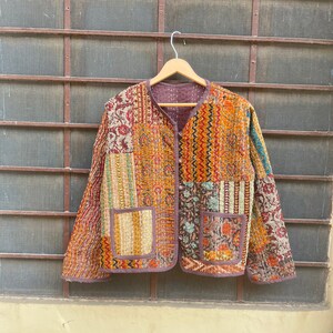 May include: A patchwork quilted jacket with a brown, orange, and yellow color scheme. The jacket has a button closure and two pockets.