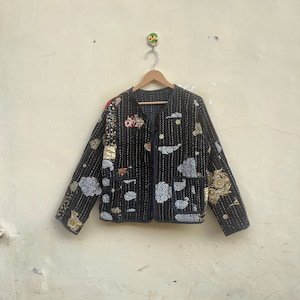 May include: A black quilted jacket with gold and silver embroidery. The jacket has a button closure and two pockets.