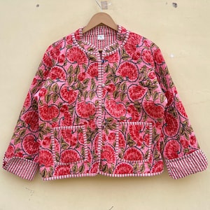 May include: A pink floral print jacket with a button closure and two pockets. The jacket has a white trim around the edges and a white and pink striped pattern on the cuffs.