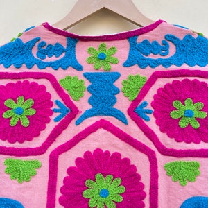 Puede incluir: Una blusa de algod&oacute;n rosa con flores bordadas de colores y patrones geom&eacute;tricos. El bordado est&aacute; hecho en tonos de rosa, verde, azul y blanco.